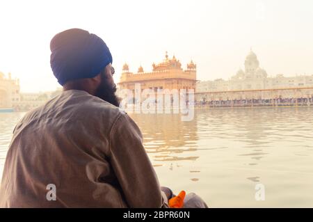 Unidentifiable Punjabi Sikh pilgrim devotee 'Nihang Warrior' sitting by the holy pool and meditating in front of Golden Temple ('Harmandir Sahib Darba Stock Photo