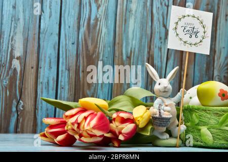 Colored easter eggs, easter rabbit and spring flowers on a wooden  background with copy space. Greeting card, Easter background Stock Photo