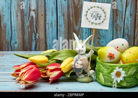 Colored easter eggs, easter rabbit and spring flowers on a wooden  background with copy space. Greeting card, Easter background Stock Photo