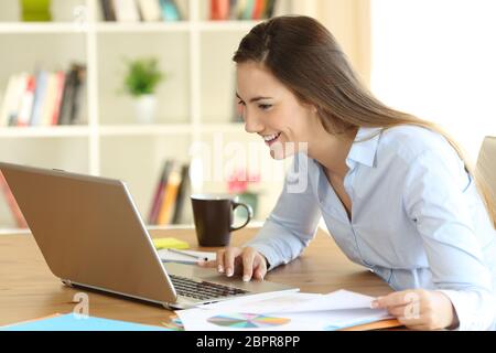 Happy self employed working on line with a laptop at home Stock Photo