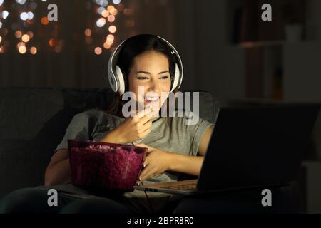 Single woman watching online tv in the night sitting on a couch in the living room at home Stock Photo