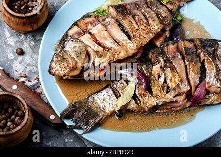 Grilled whole fish loaded with citrus,vegetable and spices on rustic table Stock Photo