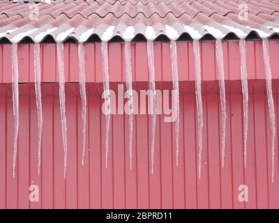 Long icicles on the red roof Springtime Stock Photo