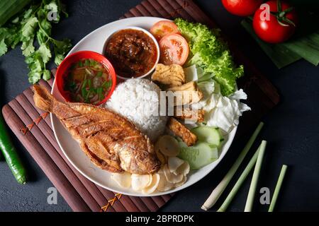 Fried tilapia fish and rice, popular traditional Malay or Indonesian local food. Flat lay top down overhead view. Stock Photo