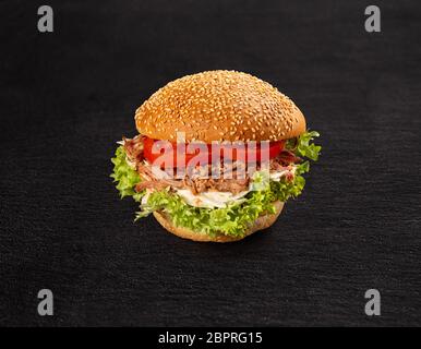 Pulled pork burger with fresh salad and tomato on dark background Stock Photo