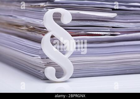 Close-up Of Red Paragraph Symbol Leaning On Documents