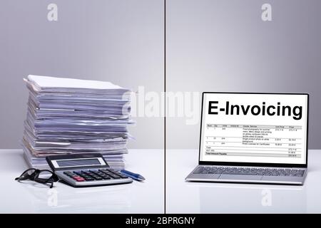 Stacked Of E-invoice Paper And Calculator Is Replace With New Technology Against White Background Stock Photo