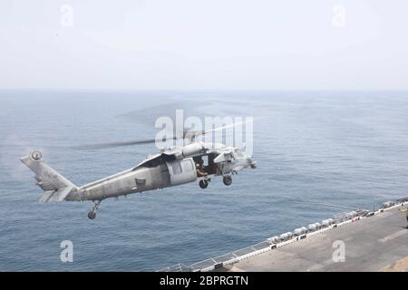 200515-N-GC472-2019  ARABIAN GULF (May 15, 2020) - An MH-60S Seahawk, attached to the dragon whales of helicopter sea combat squadron (HSC) 28, takes off from the flight deck of the amphibious assault ship USS Bataan (LHD 5), May 15, 2020. Bataan is the flagship for the Bataan Amphibious Ready Group and, with embarked 26th Marine Expeditionary Unit, is deployed to the U.S. 5th Fleet in support of maritime security operations to reassure allies and partners and preserve the freedom of navigation and the free flow of commerce in the region. (U.S. Navy photo by Mass Communication Specialist 2nd c Stock Photo