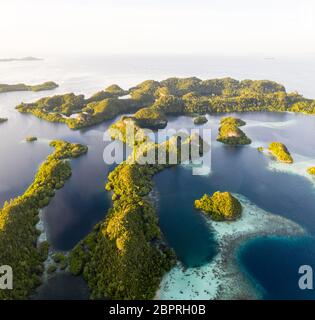 The limestone islands found throughout Raja Ampat are surrounded by coral reefs. This remote region is a favorite destination for scuba divers. Stock Photo