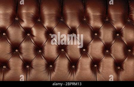 Background texture of dark brown capitone genuine leather, retro Chesterfield style soft tufted furniture upholstery with deep diamond pattern and but Stock Photo