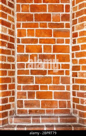 Recess arch frame in old brick wall. Detail of decorative portal in a red brick wall. Recess in a brick wall. Red brick masonry with recesses. Recess Stock Photo