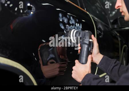 Auto polishing process. Detailing worker polishes car body Stock Photo