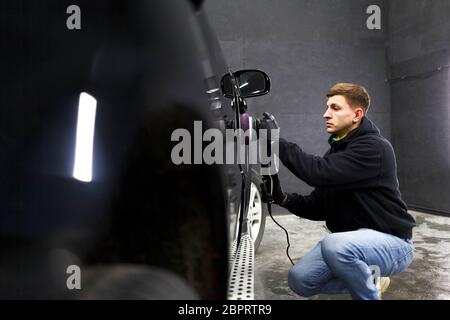 Worker of the detailing center polishes car body Stock Photo