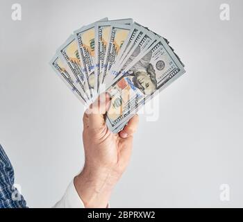 male hand holding a stack of one hundred dollar bills on a white background Stock Photo