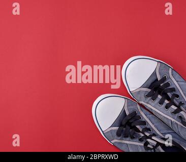 pair of black old textile sneakers  on a red background, copy space Stock Photo