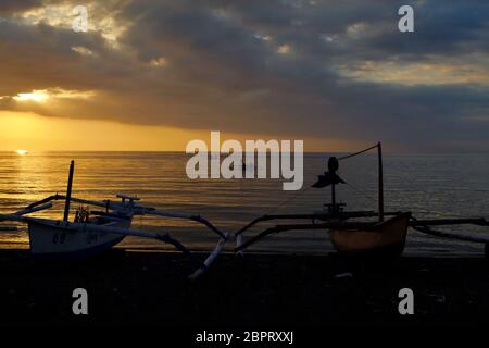 Fishing boats on a cloudy afternoon at the beach of Lovina town in Bali, Indonesia, with other boats in the background already sail on sea waters carrying tourists to find dolphins to watch--an attraction that more popularly conducted in the morning. Archival image. Photo: Reynold Sumayku Stock Photo