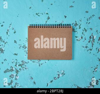 empty notebook on a black iron spring with brown empty sheets on a green background, close up Stock Photo