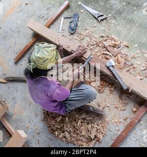 Unrecognizable carpenter working with manual tools in traditional carpentry shop in developing country. Heavy labour intensive manual work. Stock Photo