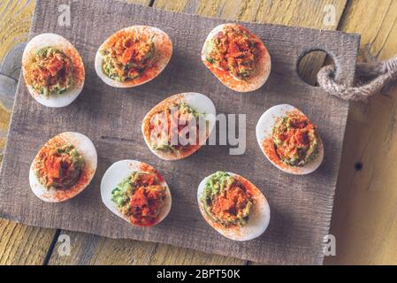 Guacamole and bacon deviled eggs on cutting board Stock Photo