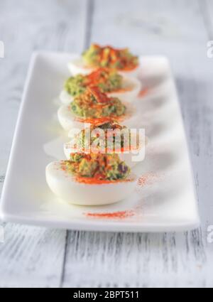 Guacamole and bacon deviled eggs on the white plate Stock Photo