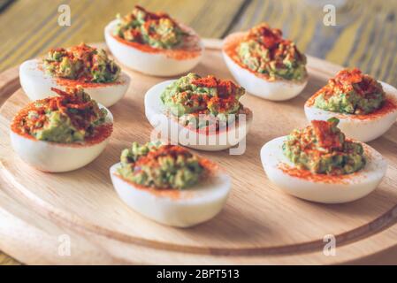 Guacamole and bacon deviled eggs on cutting board Stock Photo