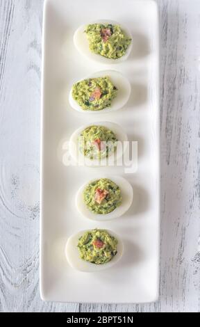 Guacamole and bacon deviled eggs on the white plate Stock Photo