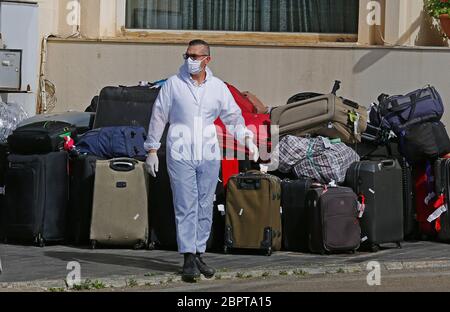 Beirut, Lebanon. 19th May, 2020. A worker wearing a face mask stands near the luggage belonging to people returning from abroad at a hotel in Beirut, Lebanon, on May 19, 2020. Lebanon's number of COVID-19 infections increased on Tuesday by 23 cases to 954, while the death toll remained unchanged at 26, the National News Agency reported. Credit: Bilal Jawich/Xinhua/Alamy Live News Stock Photo