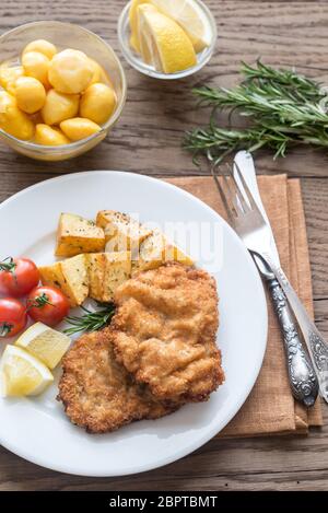 Portion of schnitzel with garnish on the wooden table Stock Photo