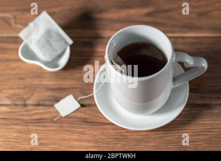 Chinese hot black tea with ceramic mugs with tea bag on a wooden table Stock Photo