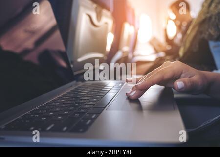 Closeup image of a woman using and touching at laptop computer touchpad while sitting in the cabin Stock Photo