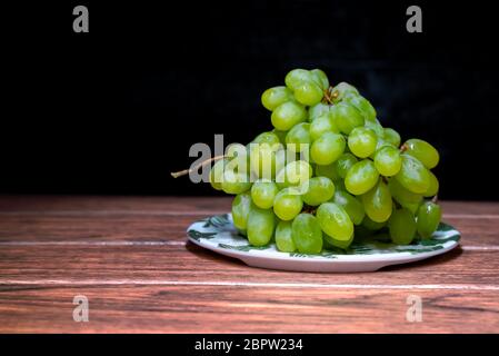 green seedless grapes in a white bowl on a wooden board Stock Photo