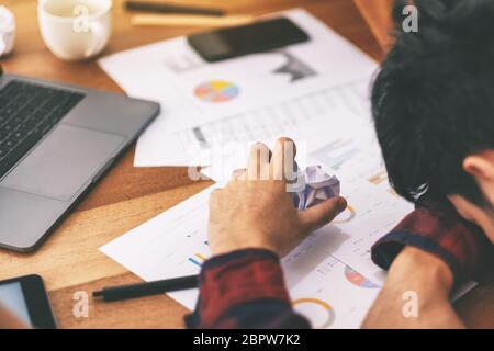 A businessman working with feeling frustrated and stressed with screwed up papers and laptop on table in office Stock Photo