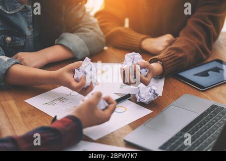 A businessman screwed up papers by hand with laptop, tablet and paper work on the table in a meeting Stock Photo