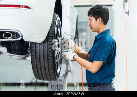 Asian mechanic checking and repairing the car wheels in maintainance service center which is a part of showroom, technician or engineer professional w Stock Photo
