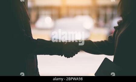 Silhouette image of two people shaking hands Stock Photo