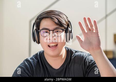 Asian business man waving hand for say hello when making video call to friend with social distancing, smiling female taking video blog recording vlog, Stock Photo