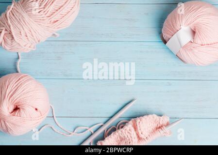 Top view of winding wools and knitting pattern on a light blue wooden background. Stock Photo