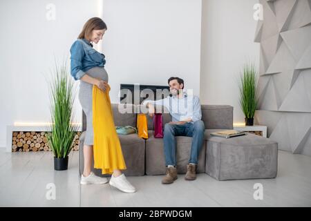 Young pregnant woman trying a yellow skirt on Stock Photo