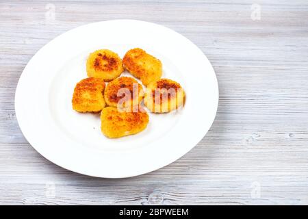 portion of fried chicken nuggets on white plate on gray wooden board Stock Photo