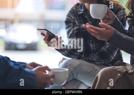 People using phone, talking and drinking coffee together Stock Photo