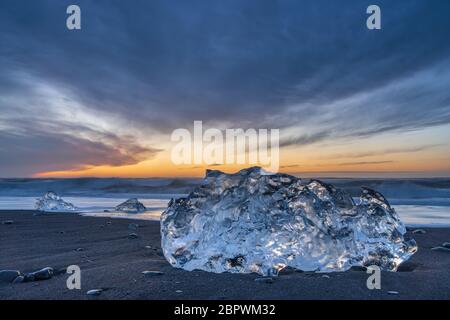 Diamond beach, South Iceland - February 27, 2019 : Sunrise at Diamond beach, near Jokulsarlon glacier lagoon, with a big ice block in the foreground Stock Photo