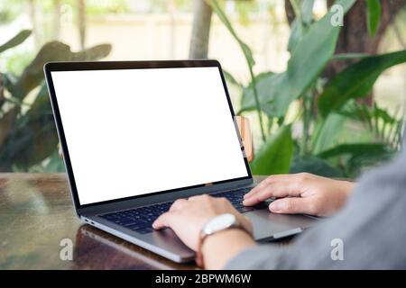 Mockup image of a woman using and typing on laptop with blank white desktop screen on wooden table Stock Photo