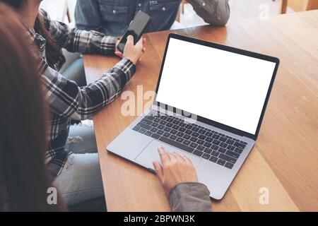 A woman using and touching on mockup laptop computer touchpad with colleagues in meeting Stock Photo