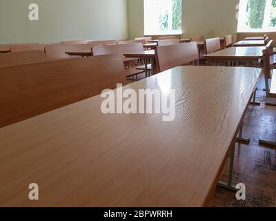 School classroom with three-row desks and large windows. Student audience with wide desks in three rows and a large window. Stock Photo