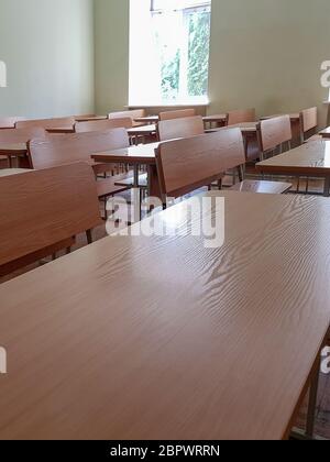 School classroom with three-row desks and large windows. Student audience with wide desks in three rows and a large window. Stock Photo