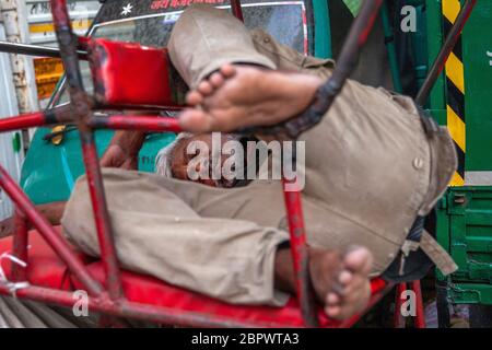 An Indian rickshaw puller sleeps in his rickshaw on a deserted road, as India remains under an unprecedented extended lockdown over the highly contagious coronavirus (COVID-19) on May 05, 2020 in New Delhi, India. Photographer: Kuldeep Singh Rohilla Stock Photo