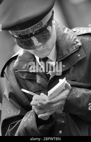 Traffic Warden writing parking ticket in the rain, Newcastle-upon-Tyne