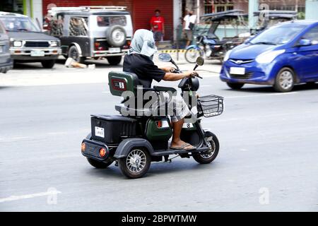 Antipolo City, Philippines - May 16, 2020: Man rides an electric tricycle to get around since public transportation were prohibited during the Covid 1 Stock Photo