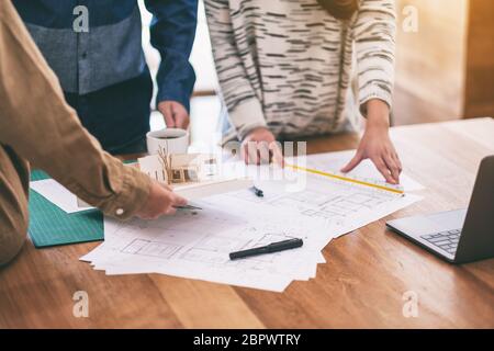 Group of an architect working and measuring scale of a mass model on table in office Stock Photo