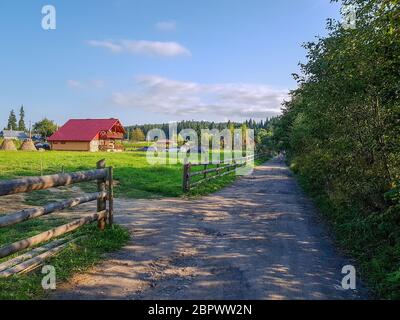 Dirt road in the Carpathian Mountains near country houses in Vorokhta before sunset. Ukraine Stock Photo